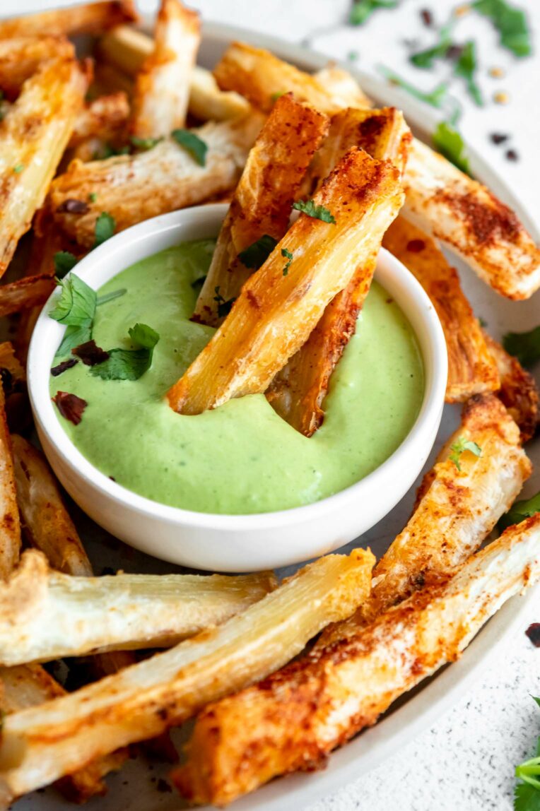 Crispy yuca fries being dipped in a sauce.