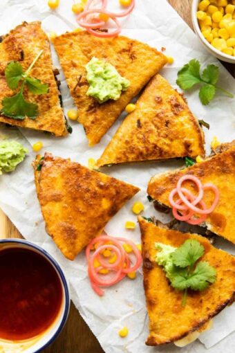 Birria Quesadillas slices with guacamole and radish.