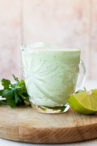 Cilantro Lime Sauce in a glass with cilantro and lime.