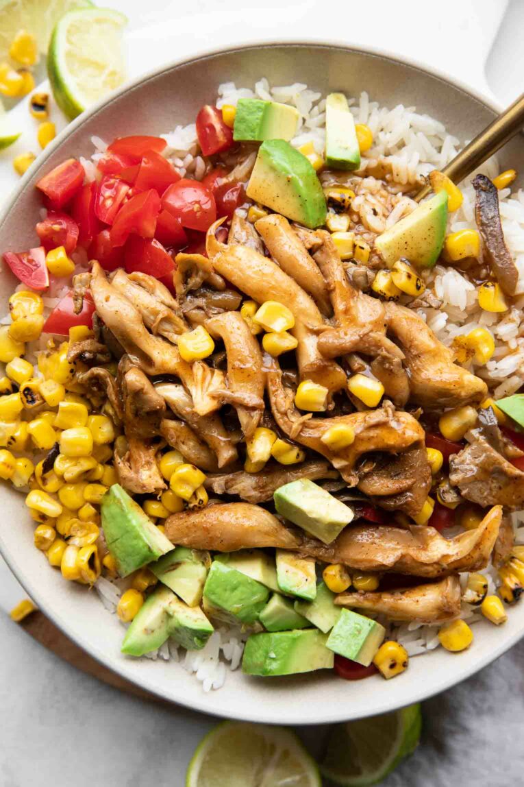 Close up of bowl with chili lime vegan shrimp, rice, tomatoes, corn, and avocado.