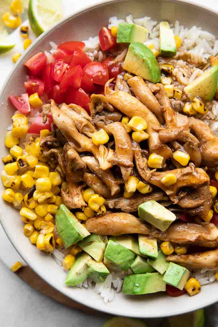 Close up of Chili Lime Vegan Shrimp Bowl with tomatoes, avocado, and corn over rice.
