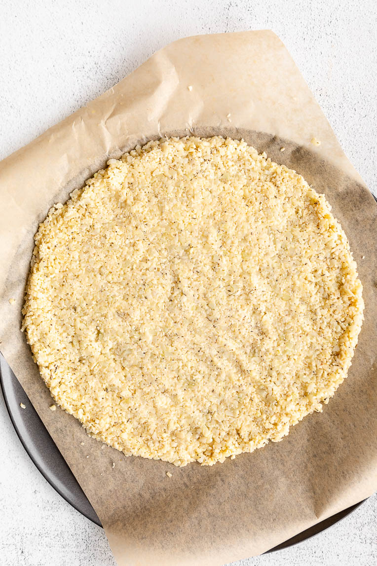Cauliflower pizza crust dough pressed into a pan.