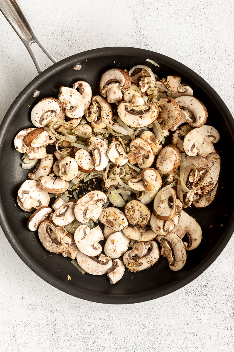 Mushrooms being sautéed in a pan.