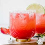 Strawberry Lime Mocktail Margarita recipe with lime, salt, and flowers in background.