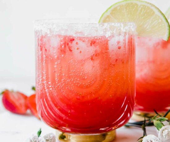 Strawberry Lime Mocktail Margarita recipe with lime, salt, and flowers in background.
