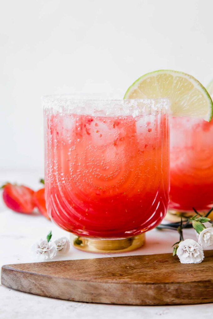 Strawberry Lime Mocktail Margarita recipe with lime, salt, and flowers in background.
