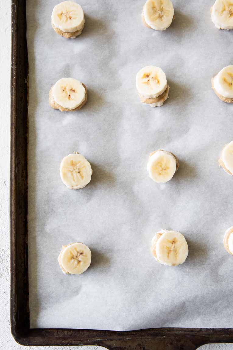 Banana bites with nut butter on a baking sheet to be frozen.