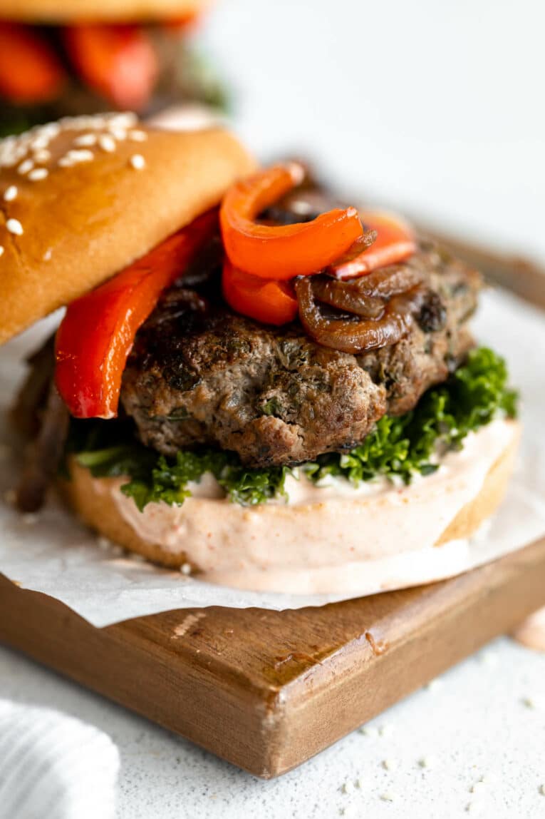 Kale beef burger with sauce and peppers.