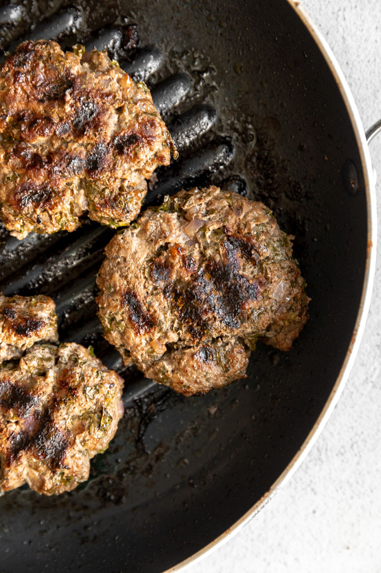 Healthy burgers being cooked in a cast iron skillet.