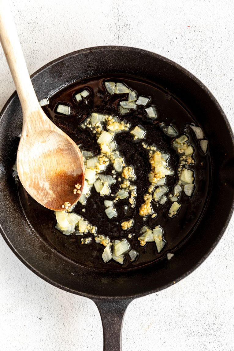 Onion being sautéed in a skillet.