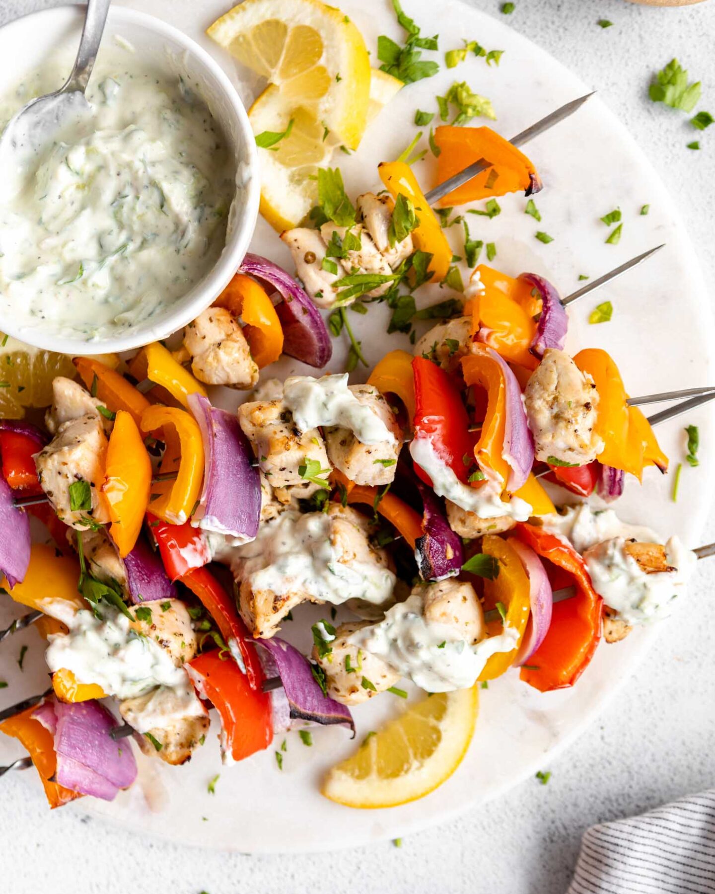 Greek Chicken Kabobs with tzatziki sauce on a platter.