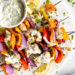 Greek Chicken Kabobs with tzatziki sauce on a platter.