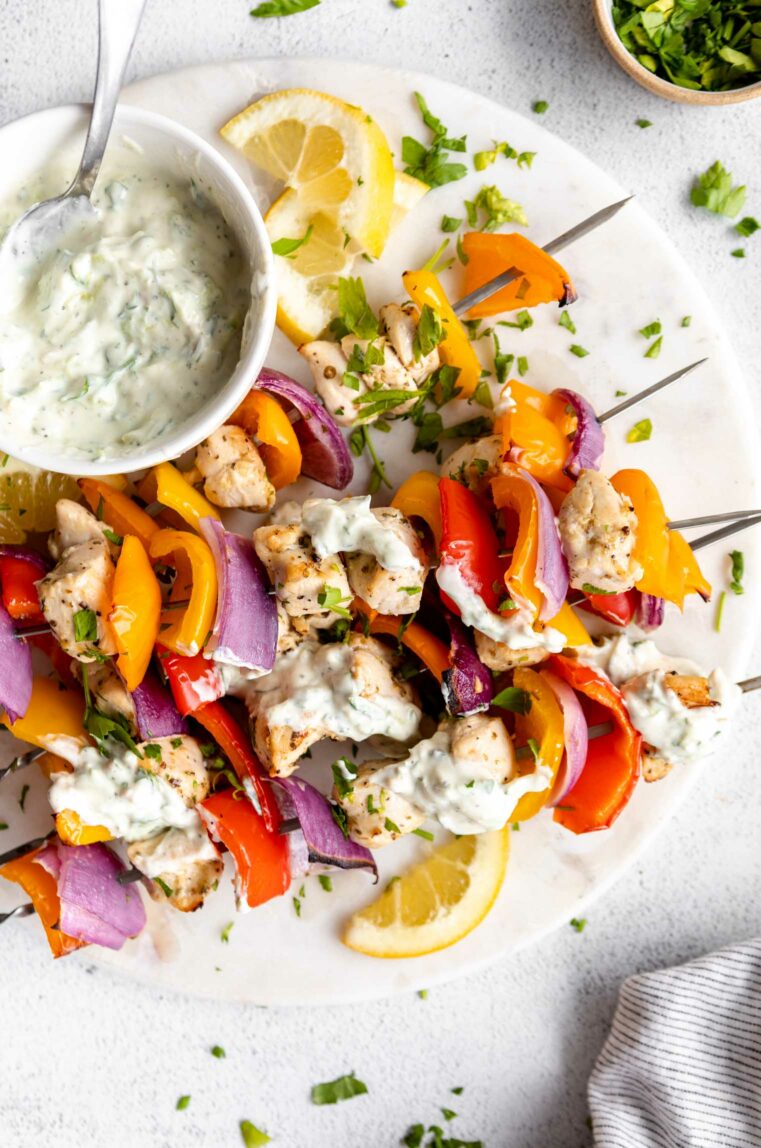 Greek Chicken Kabobs with tzatziki sauce on a platter.