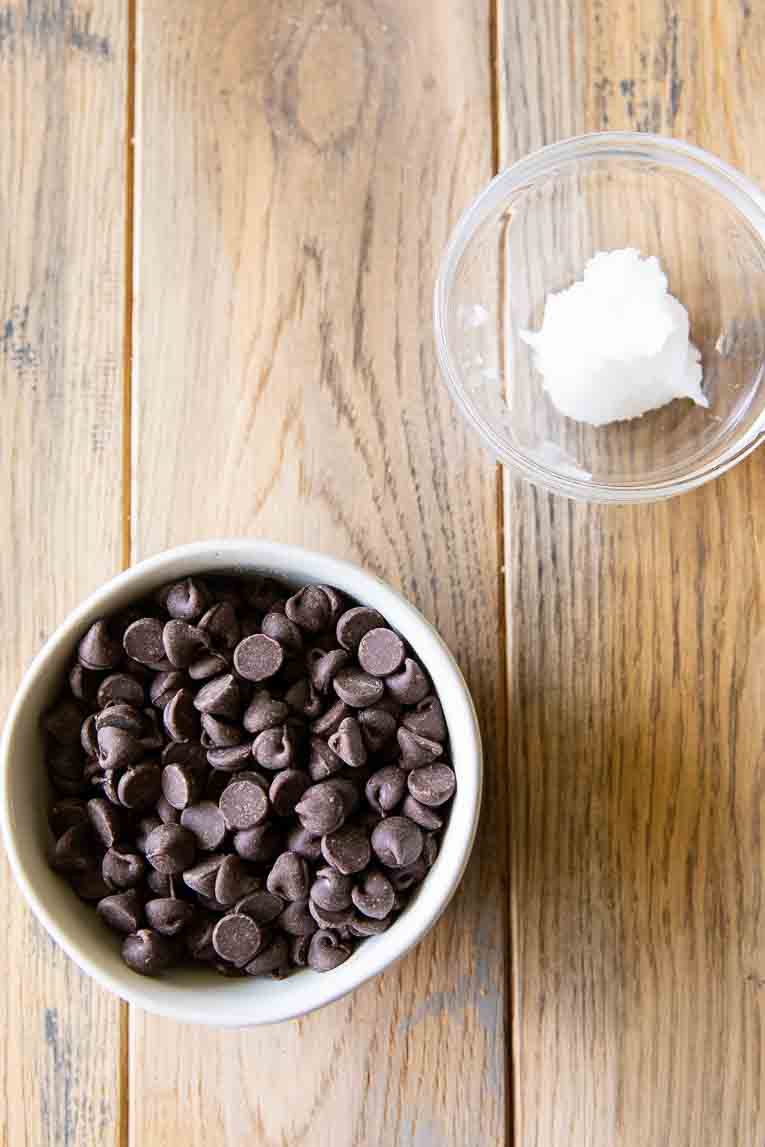 Chocolate chips and coconut oil in separate bowls.