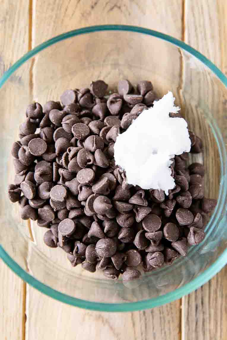Chocolate chips and coconut oil in a glass bowl.