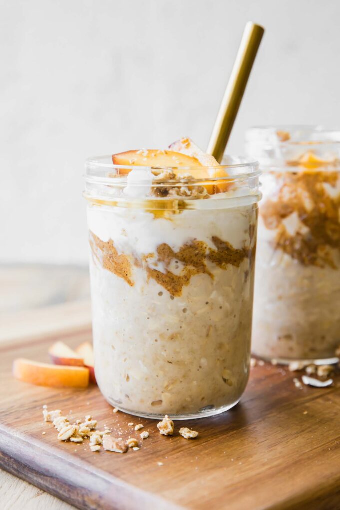 Peaches n’ Cream Overnight Oats recipe in a mason jar with a spoon.