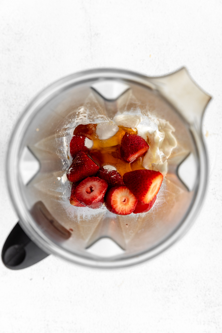 Strawberries, yogurt, and cashews being blended together.