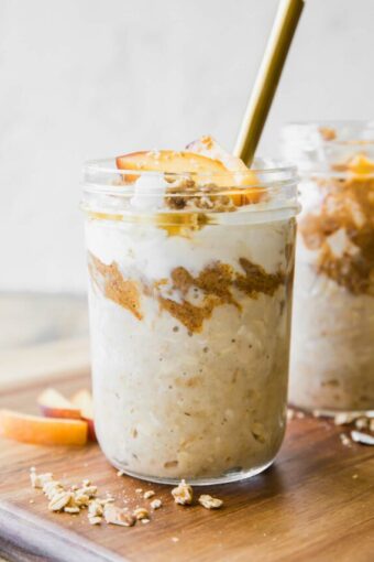 Peaches n’ Cream Overnight Oats recipe in a mason jar with a spoon.