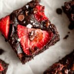 Top photo of chocolate brownie with strawberry slices.