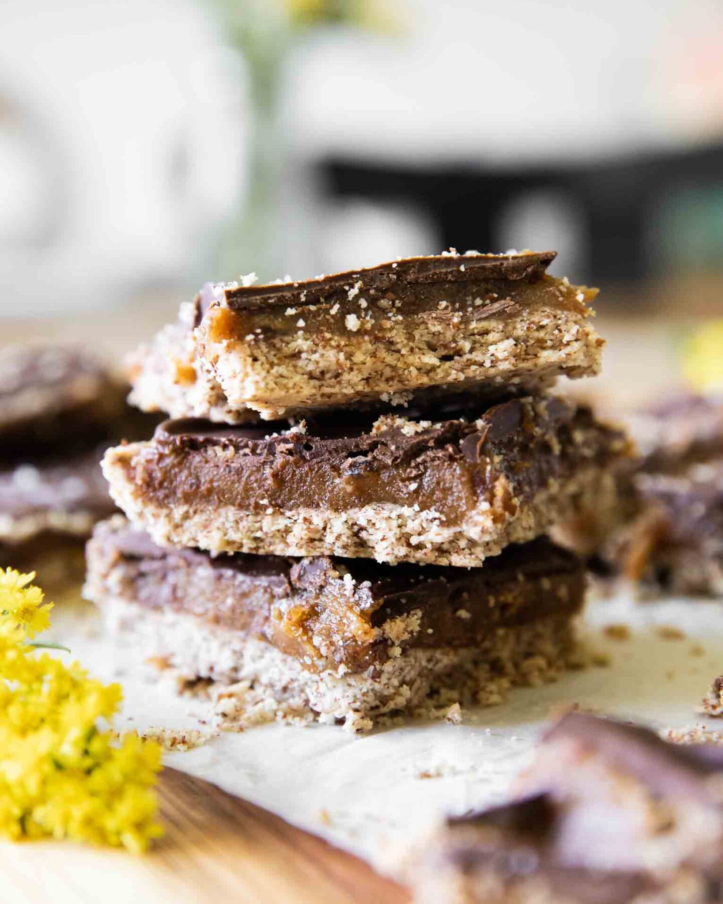 Homemade Date Twix Bars stacked on parchment paper.