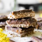 Homemade Date Twix Bars stacked on parchment paper.