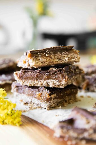 Homemade Date Twix Bars stacked on parchment paper.