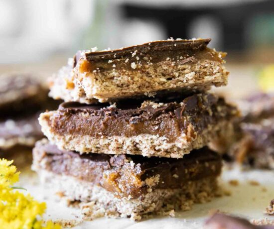 Homemade Date Twix Bars stacked on parchment paper.