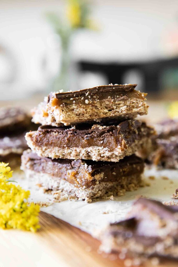 Homemade Date Twix Bars stacked on parchment paper.
