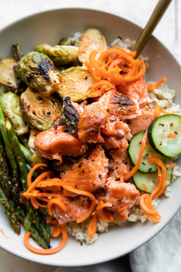 Hot Honey Salmon Bites in a bowl with sprouts, asparagus, pickles, and rice.
