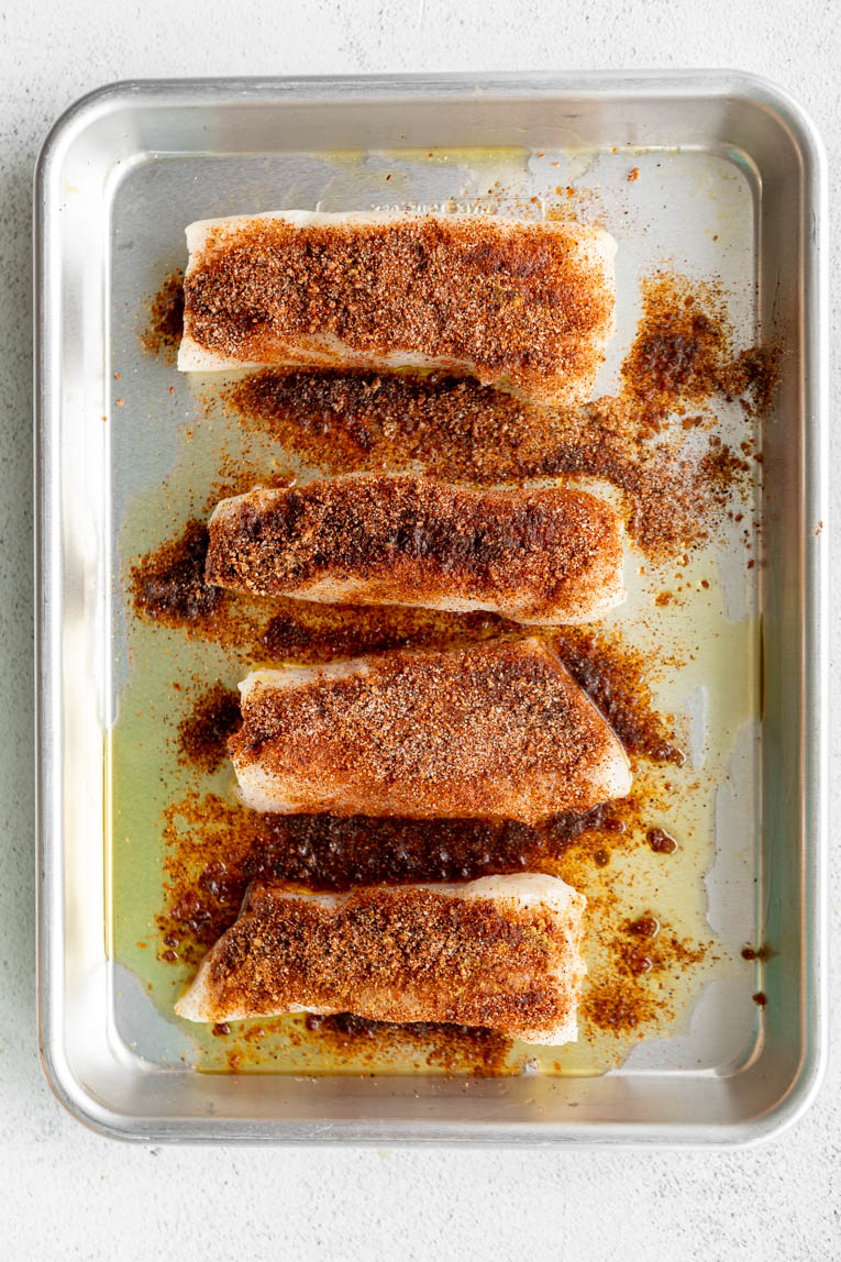 Mahi-mahi filets on a baking sheet with seasoning.