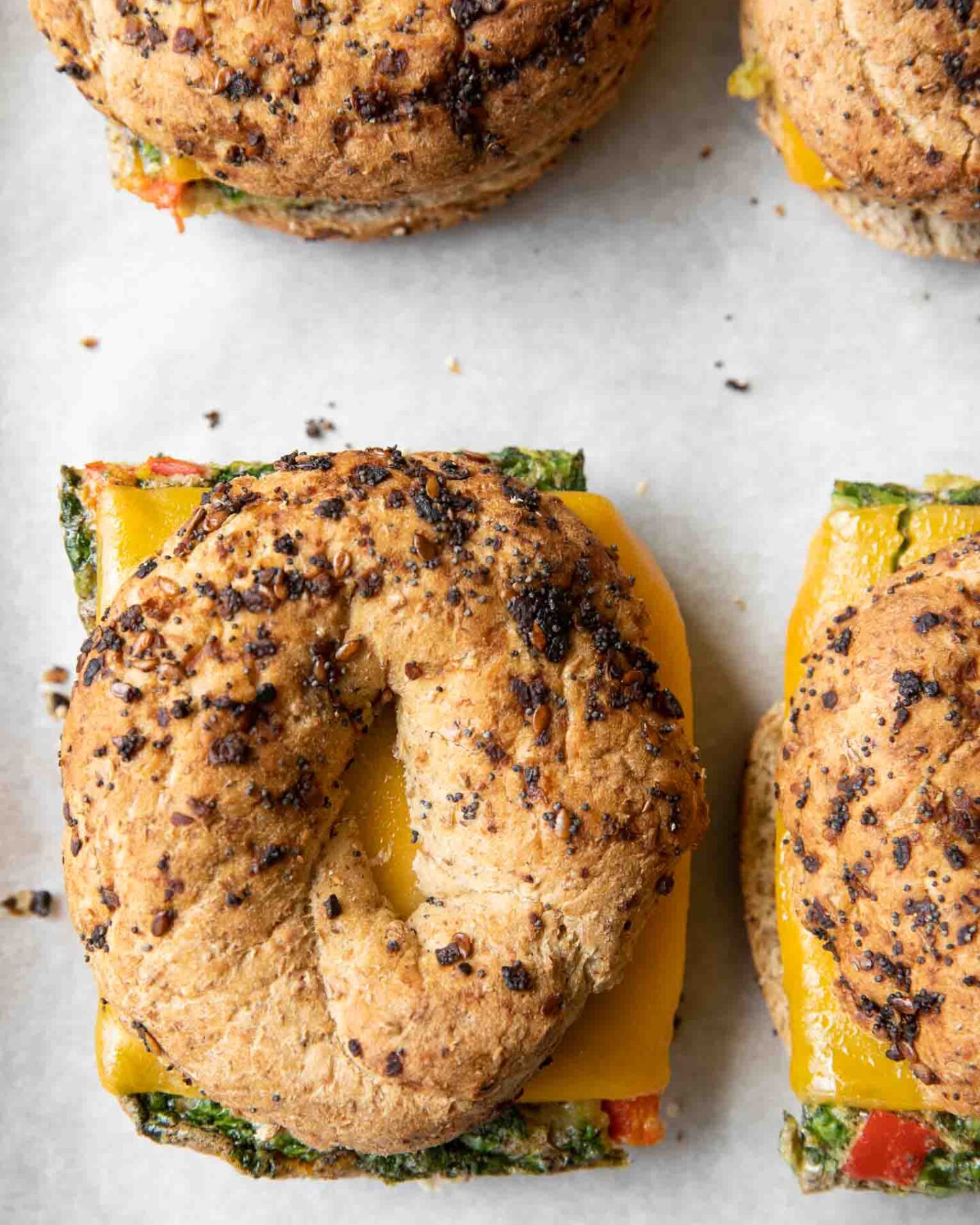 Close up of Meal Prep Breakfast Egg Bagel sandwiches on a baking sheet.