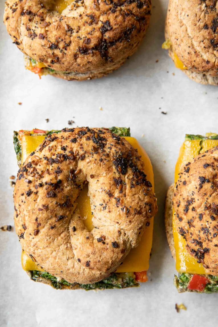 Close up of Meal Prep Breakfast Egg Bagel sandwiches on a baking sheet.