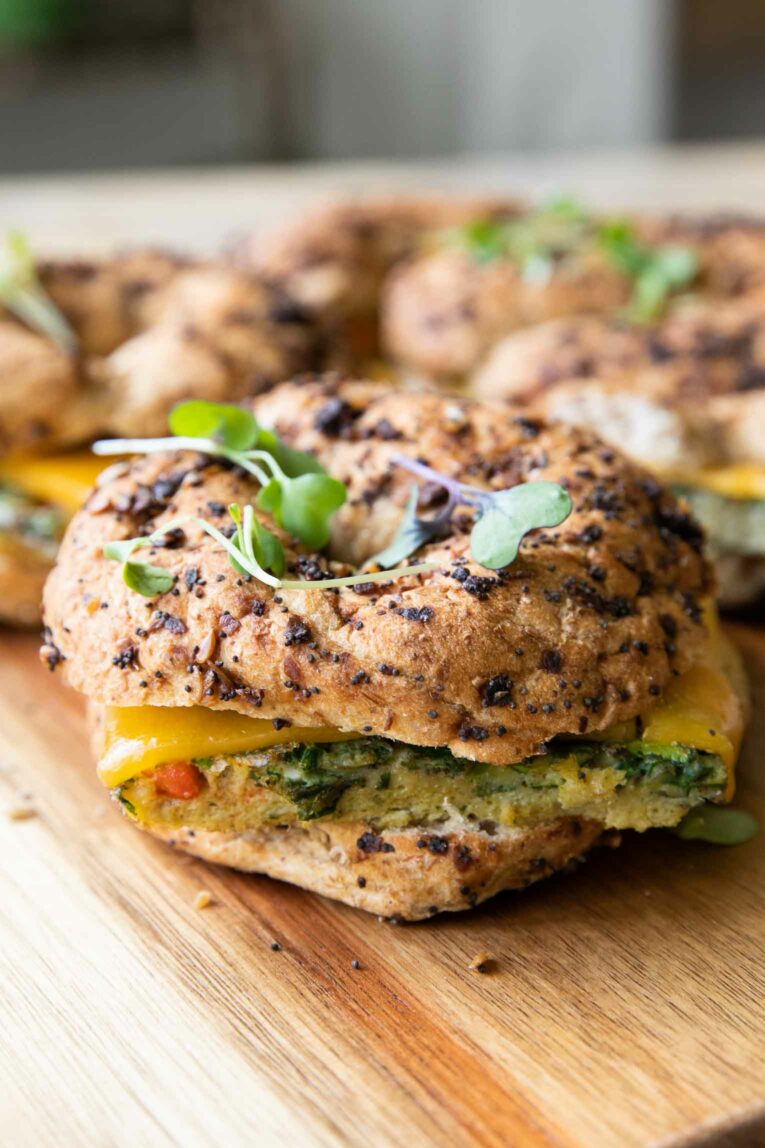 Across photo of Meal Prep Breakfast Egg Bagel sandwich with greens.