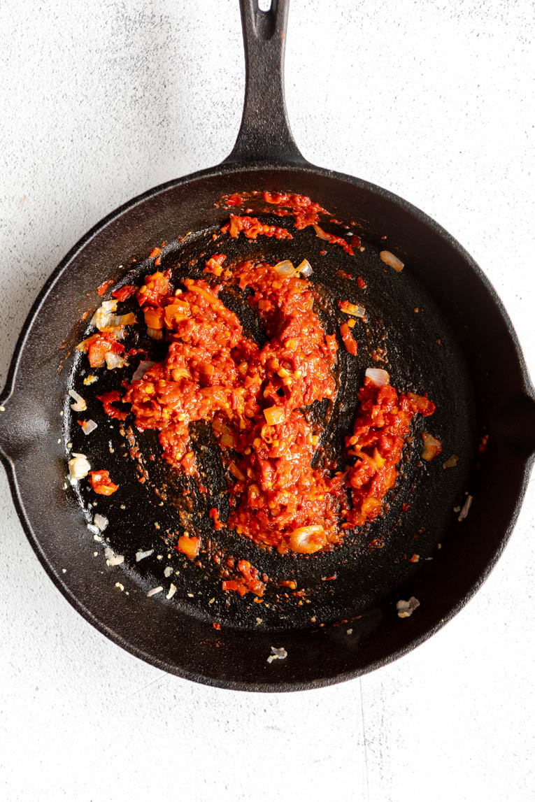 Harissa sauce and tomato paste in a skillet.