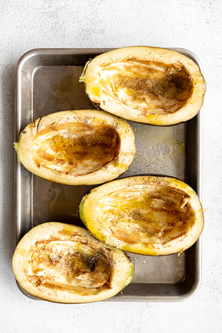 Roasted eggplant halves on a baking sheet.