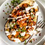 Roasted Harissa Stuffed Eggplant on a plate with yogurt drizzle.