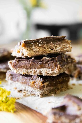 Homemade Date Twix Bars stacked on parchment paper.
