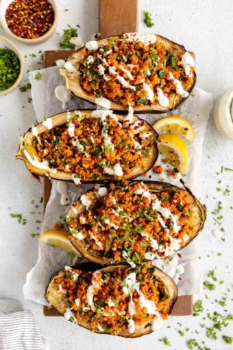Roasted Harissa Stuffed Eggplant halves on a cutting board.