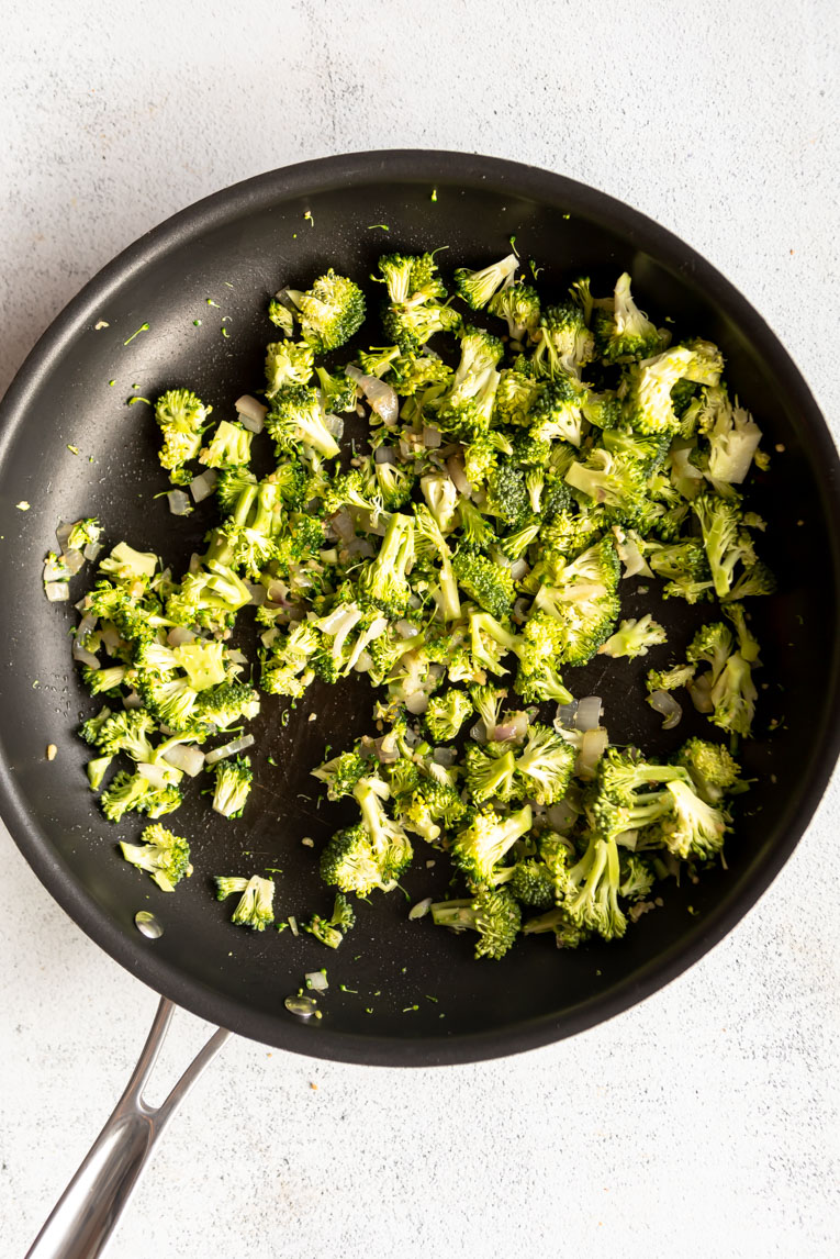Broccoli being sautéed in a pan.
