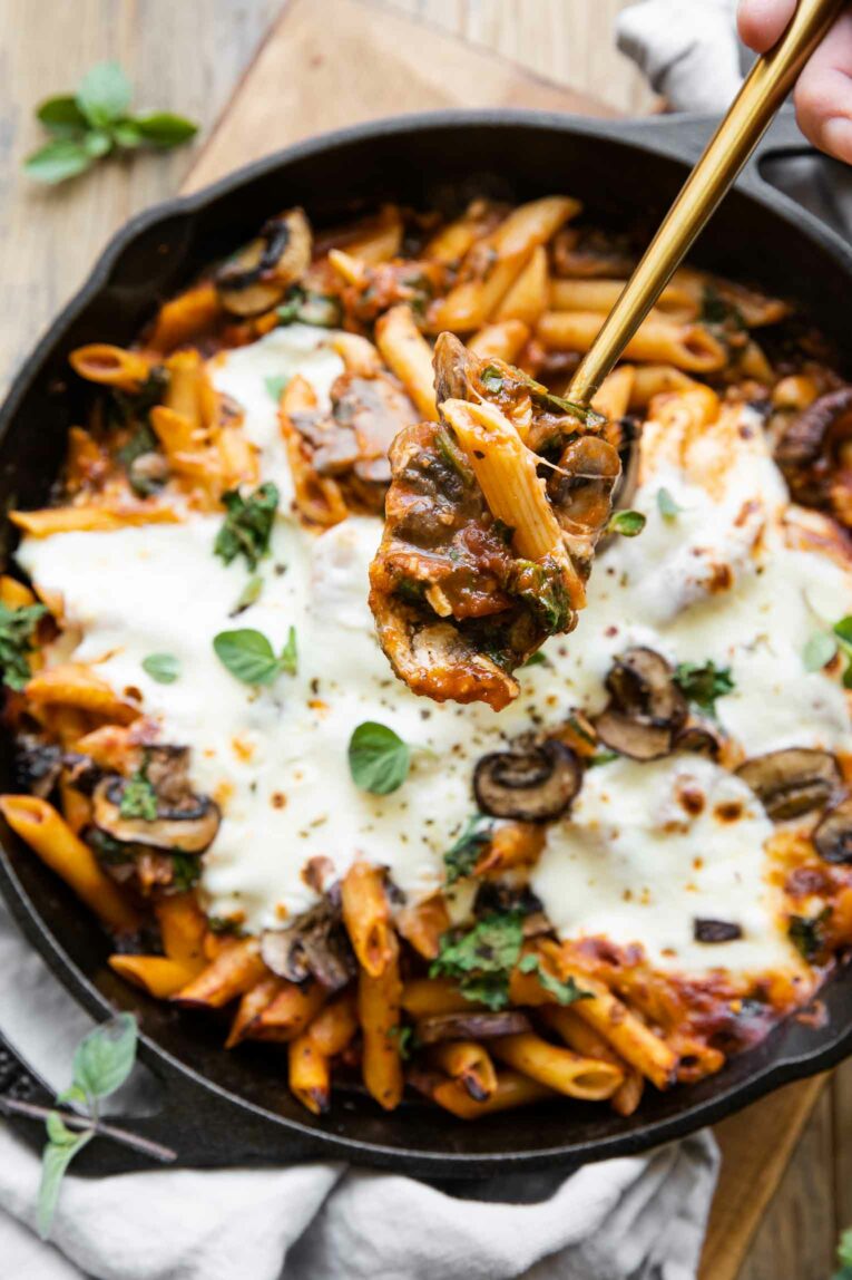 Cheesy spoonful of Mushroom & Spinach Pasta Bake being taken out of dish.