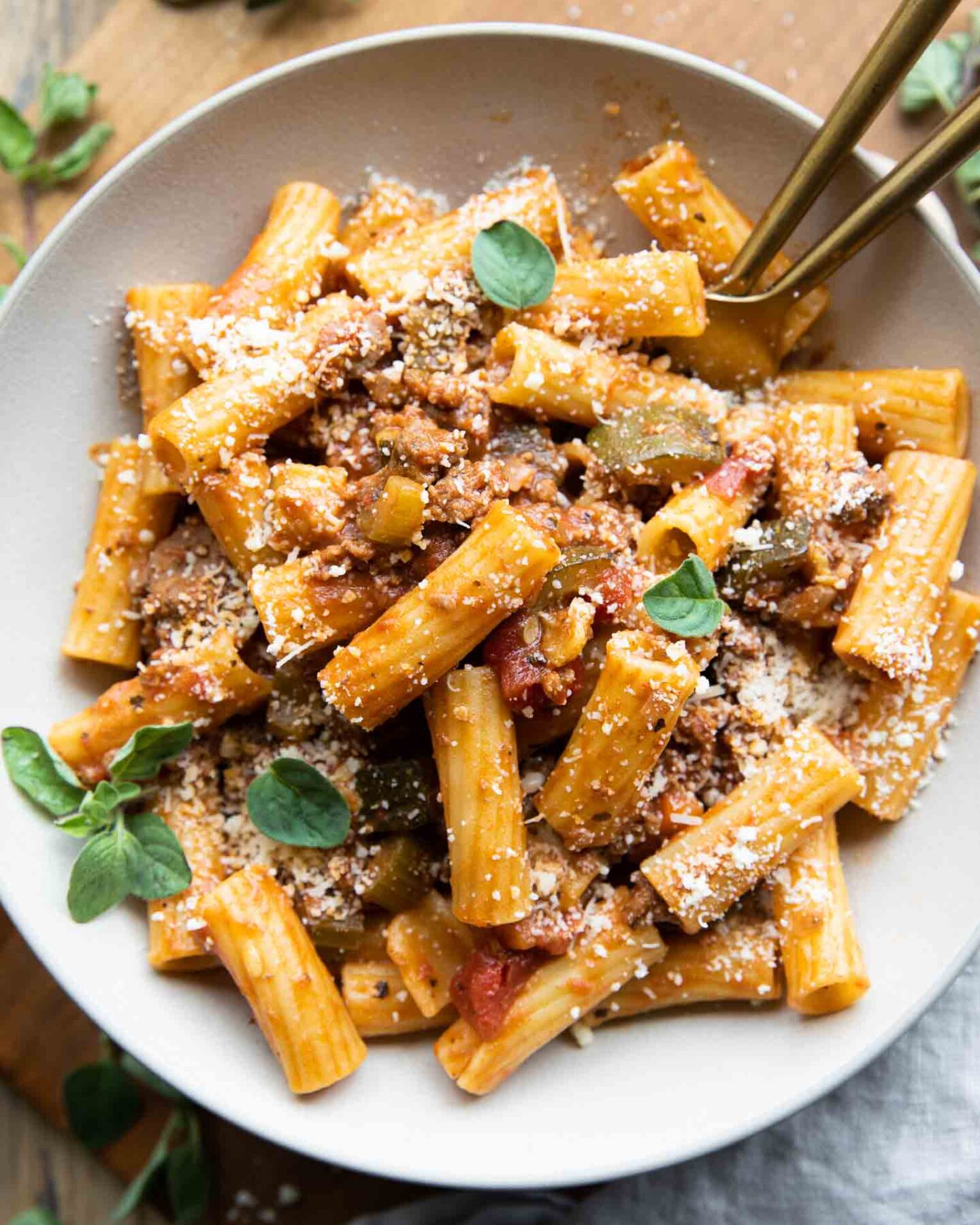 The BEST Rigatoni Bolognese recipe in a bowl with oregano and parmesan.