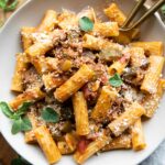 The BEST Rigatoni Bolognese recipe in a bowl with oregano and parmesan.