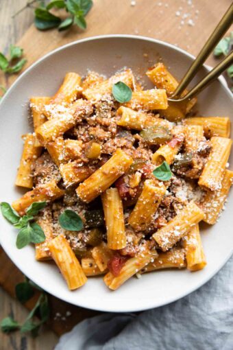 The BEST Rigatoni Bolognese recipe in a bowl with oregano and parmesan.
