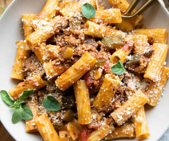 The BEST Rigatoni Bolognese recipe in a bowl with oregano and parmesan.