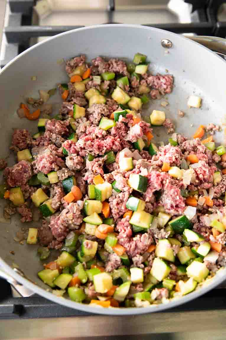 Veggies with ground beef being cooked in a pan.