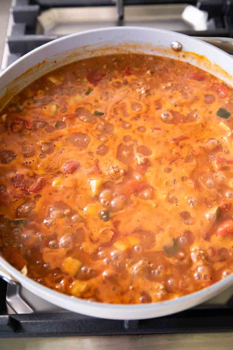 Bolognese sauce simmering in a large sauce pan.
