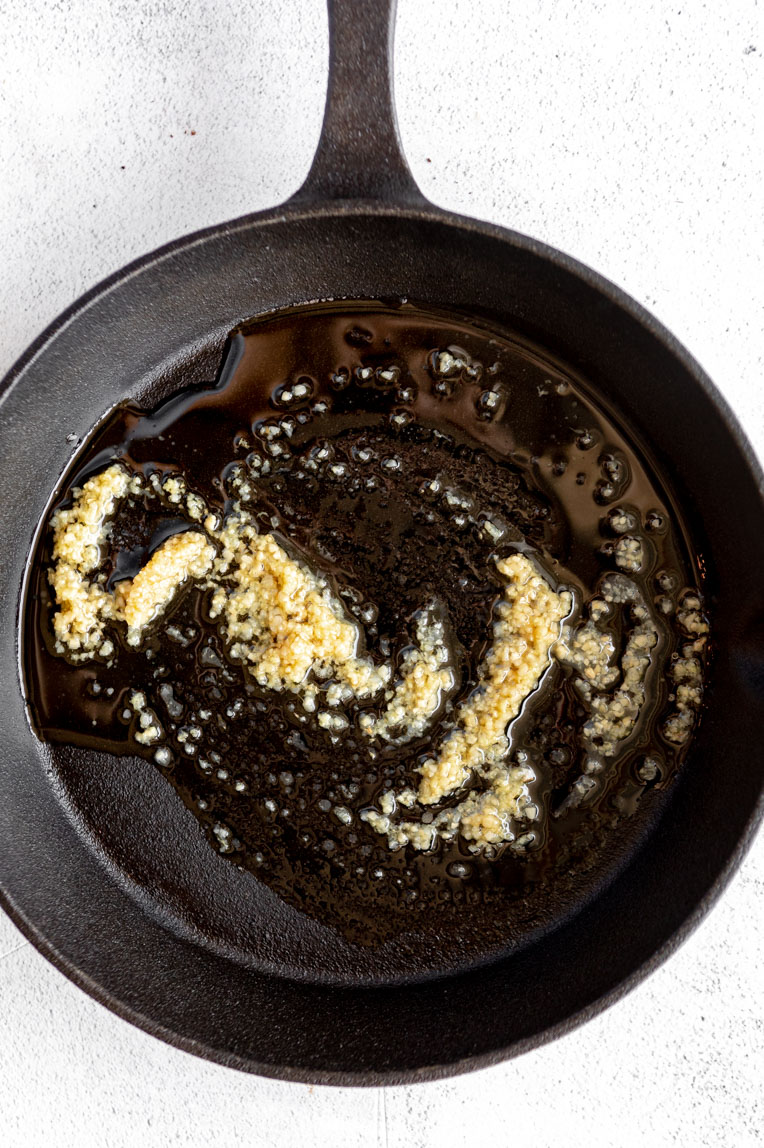 Garlic and ginger being sautéed in a pan.