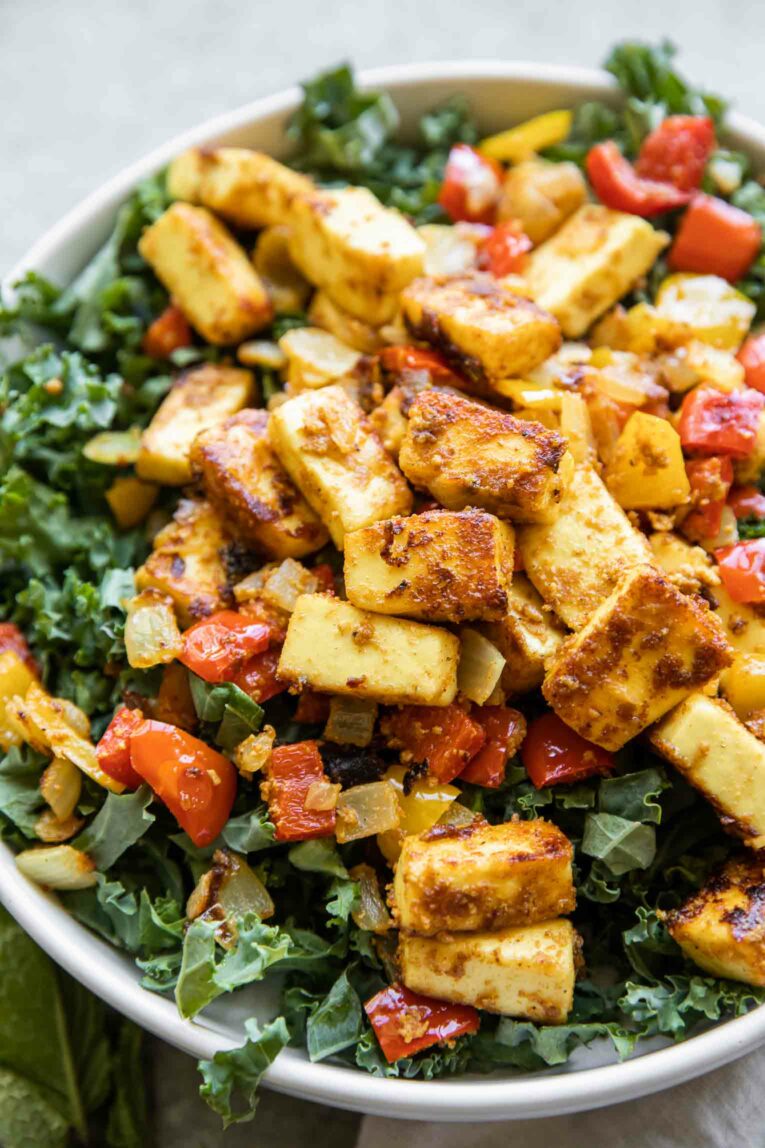Close up of tandoor paneer over chopped kale.