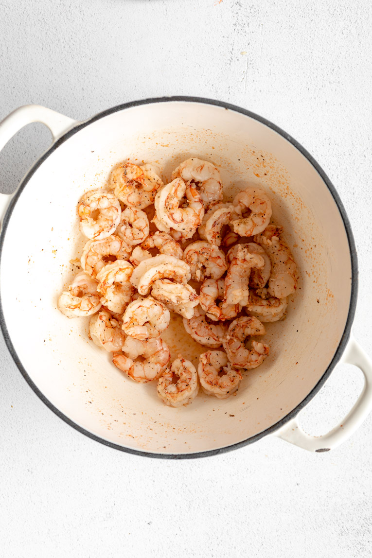 Raw shrimp being cooked in a large pan.