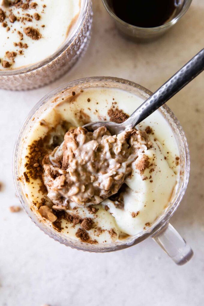 Spoonful of Tiramisu Overnight Oats with creamy yogurt topping.